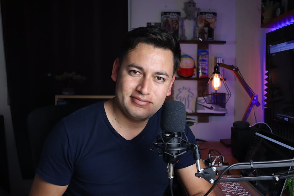 Podcast host preparing a guest briefing document beside a microphone and laptop