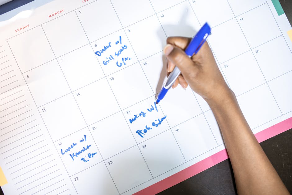 Person writing key publishing dates into a desk calendar for podcast marketing planning