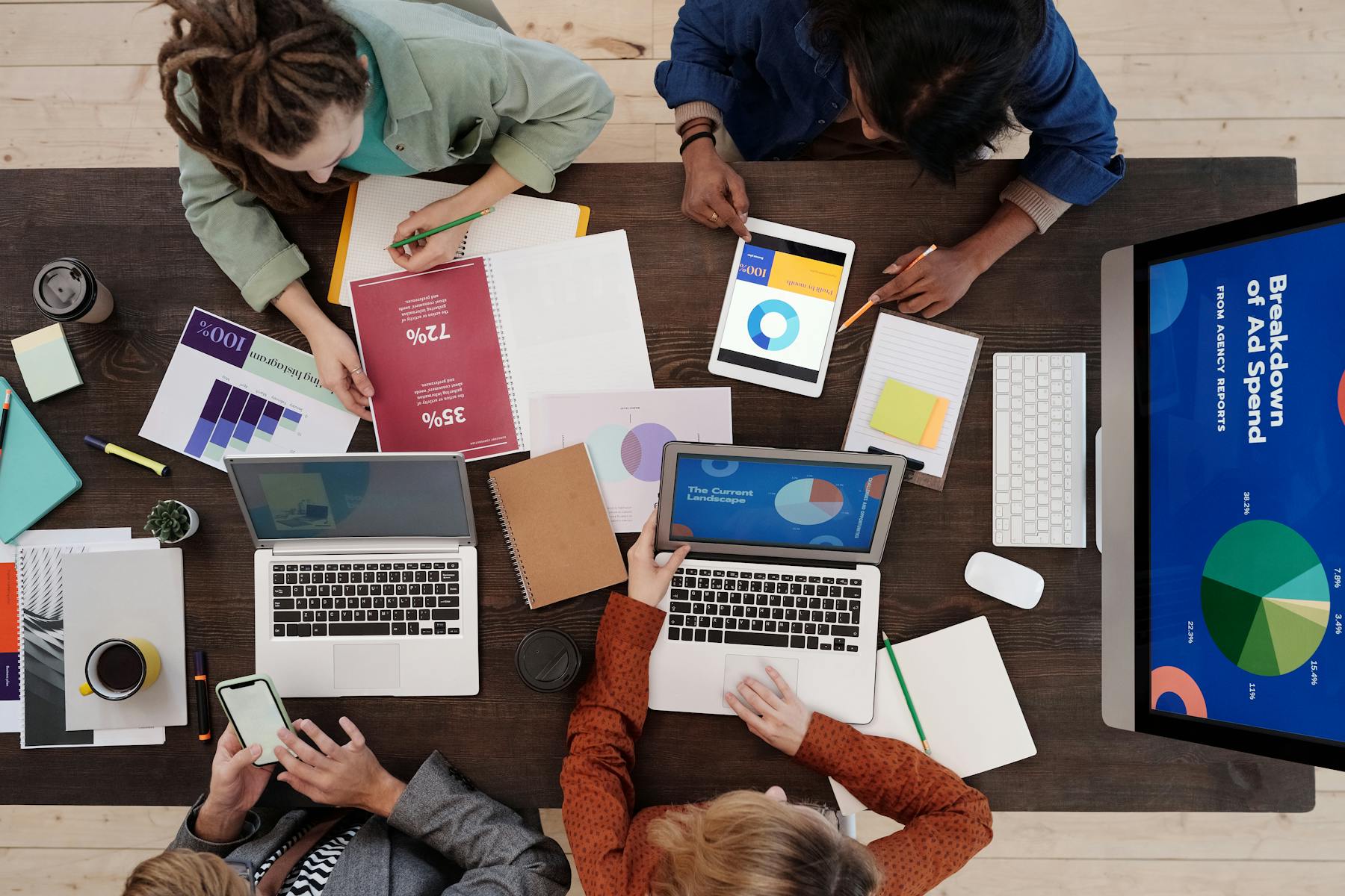 Marketing team collaborating around a desk with laptops and tablets